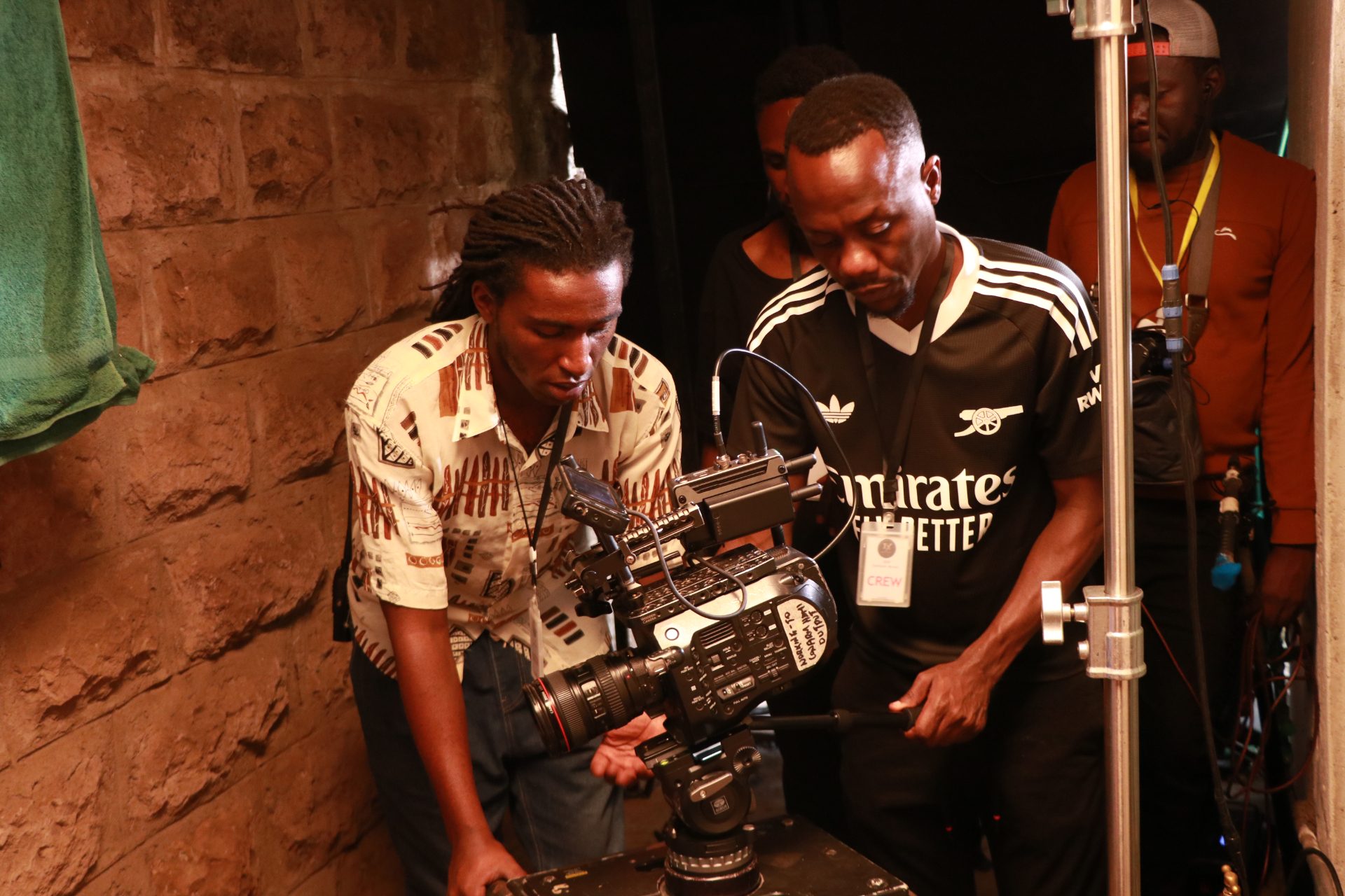Kenyan film crew on set at golden hour with neon production lights